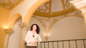 A woman standing on a staircase with ornate architectural details and a railing. - Teatrisso Hotel Palacio (Cuzcurrita de Rio Tiron)