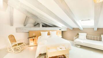 Un dormitorio moderno con una cama grande, un sofá pequeño, una mecedora y un banco de madera.
