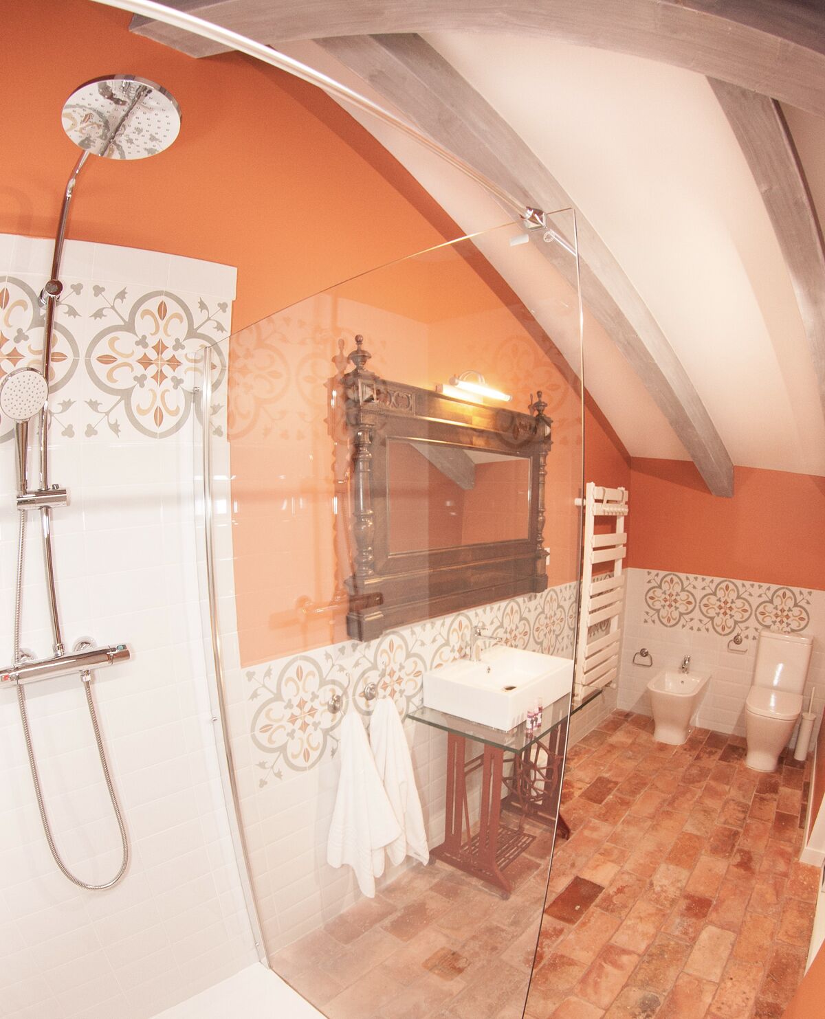 A bathroom with a glass shower enclosure, a wooden vanity, a mirror, a towel rack, and a toilet.