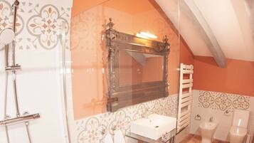 A bathroom with a glass shower enclosure, a wooden vanity, a mirror, a towel rack, and a toilet.