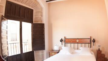 A bedroom with a large bed, a wooden headboard, a nightstand, and a dresser.
