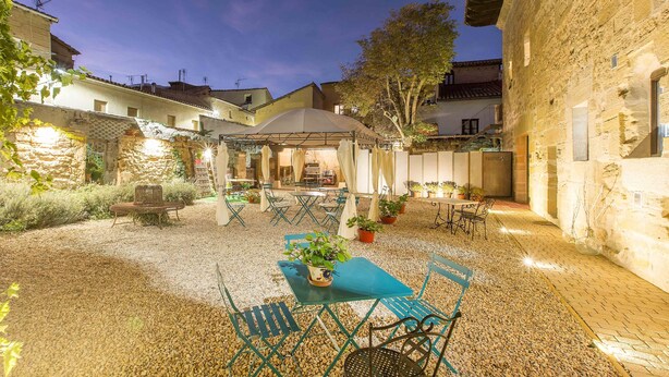 Un patio al aire libre con zona de estar cubierta, paredes de piedra y plantas en macetas.
