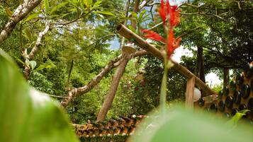 Un espacio al aire libre exuberante y verde con una estructura de bambú y un elemento acuático.