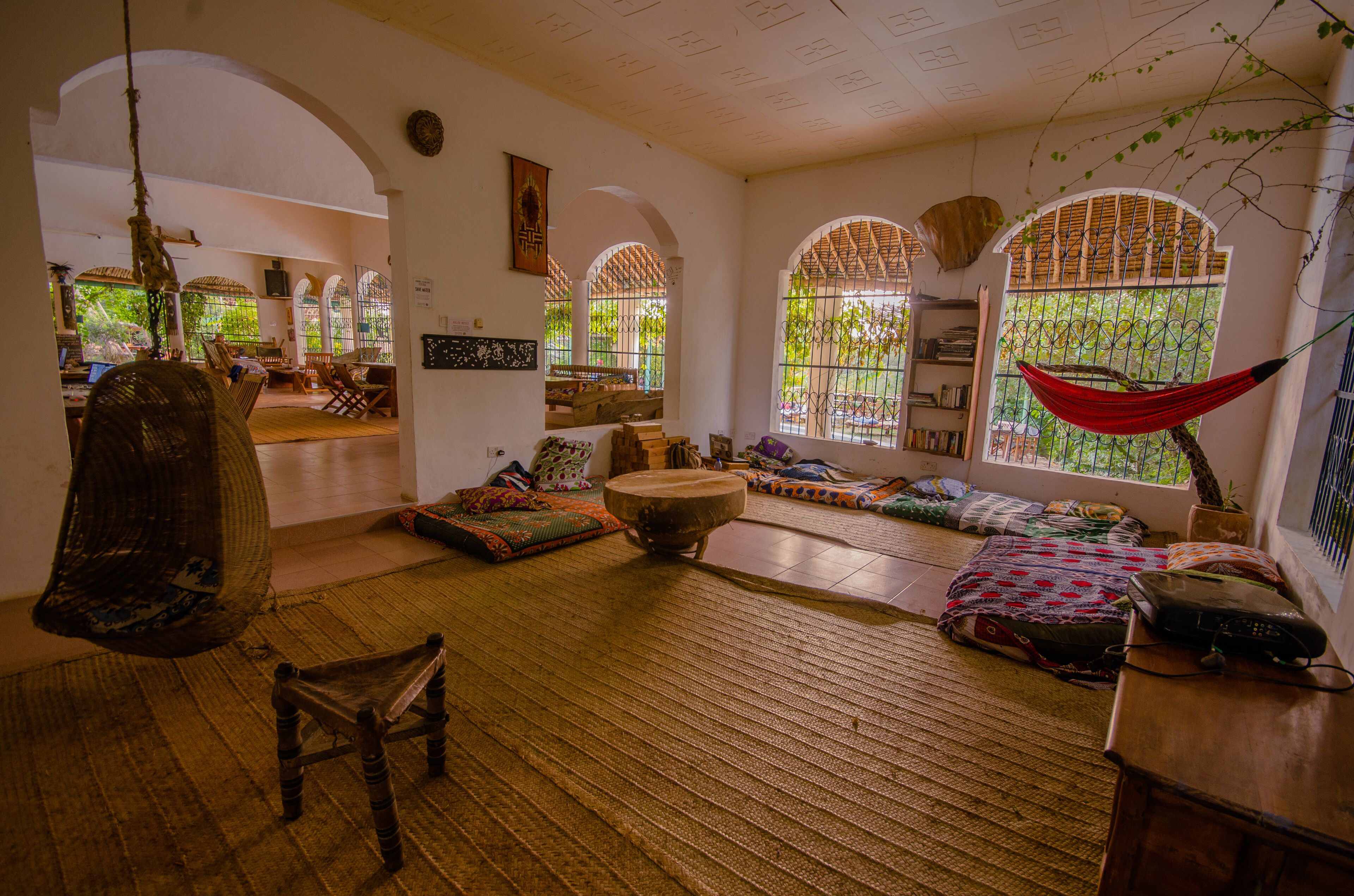 A spacious living area with a hammock, a wooden chair, and a round wooden table.