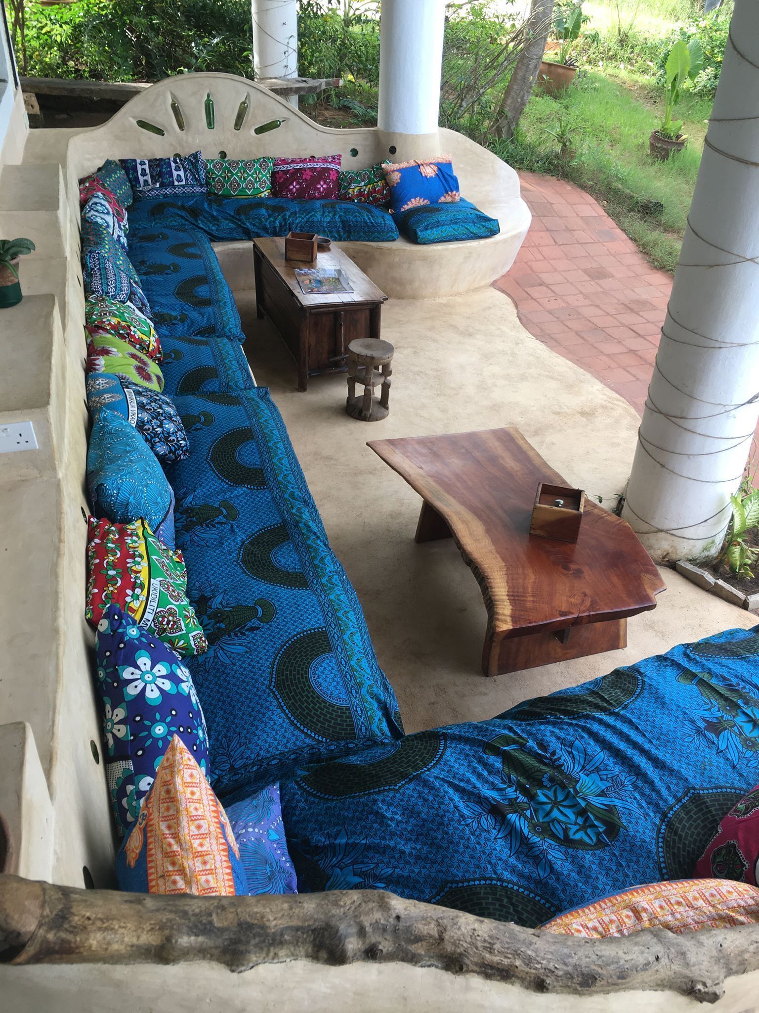 A long, curved sofa with colorful cushions, a wooden coffee table, and a small stool.