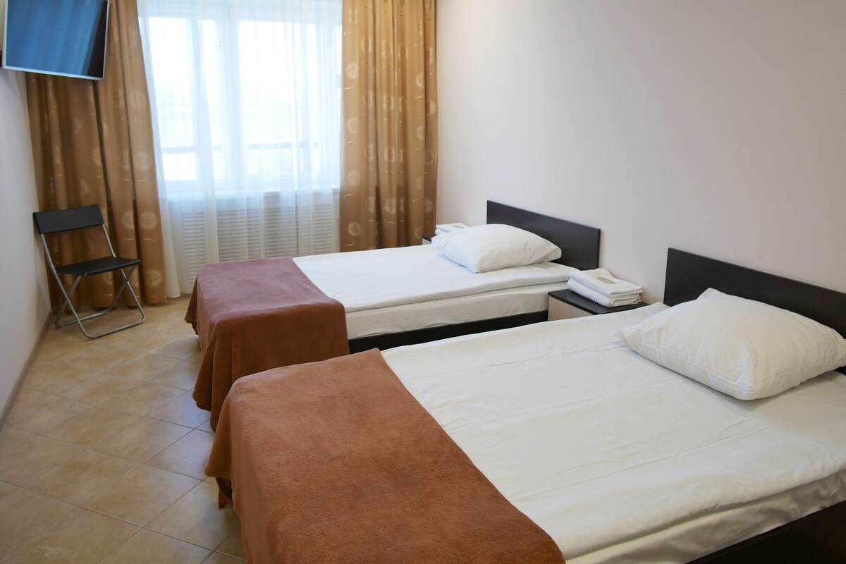 Une chambre d’hôtel avec deux lits, une télévision et une chaise.