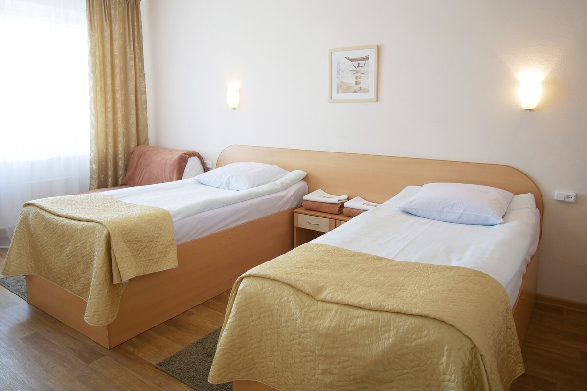 Une chambre d’hôtel avec deux lits, une table de chevet, une lampe et un tableau au mur.