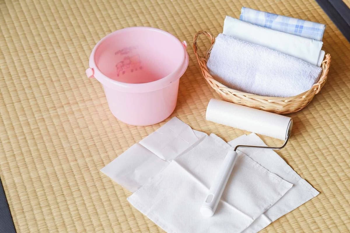 A woven mat, a pink container, a basket with towels, and a white towel.