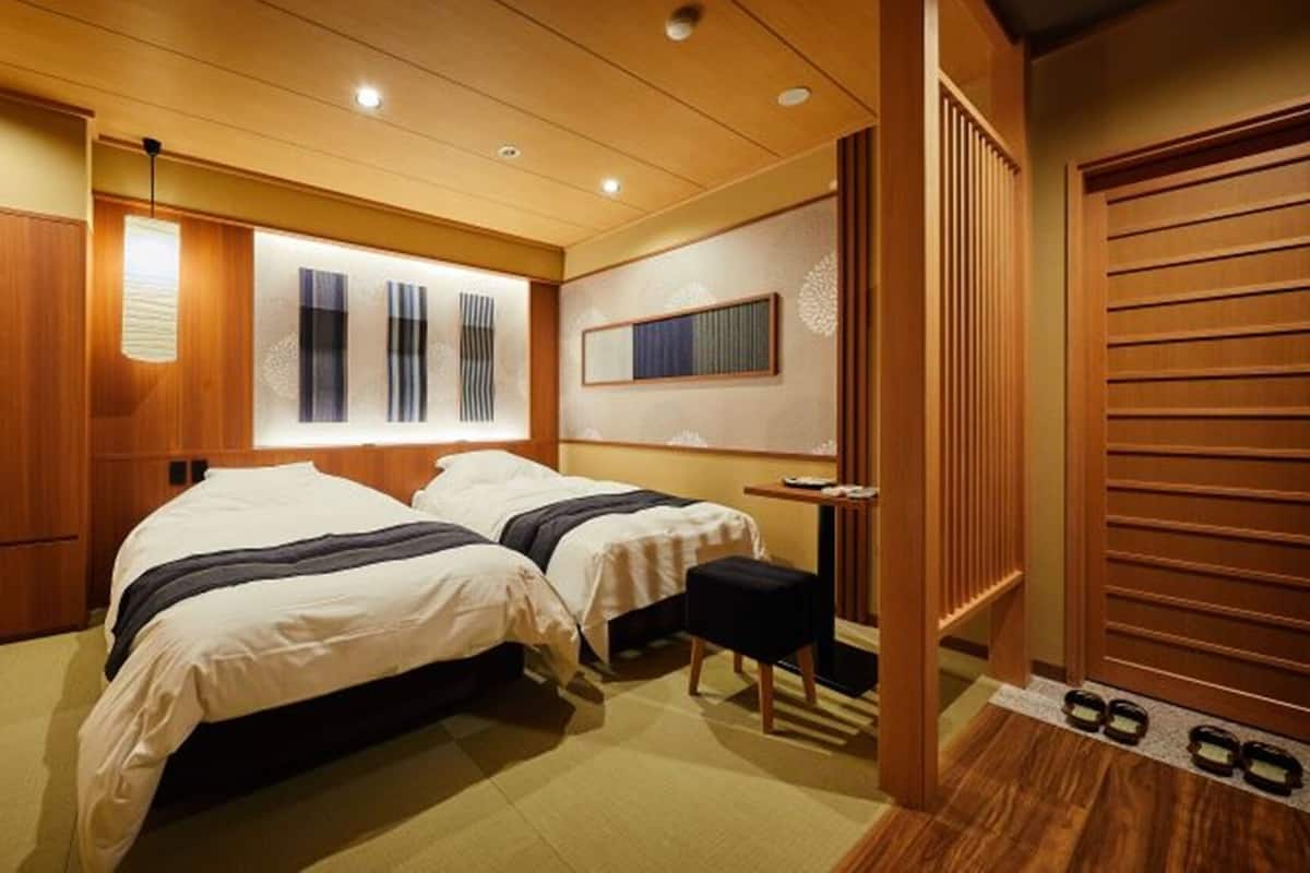 A hotel room with two beds, a desk, a mirror, and a wardrobe.