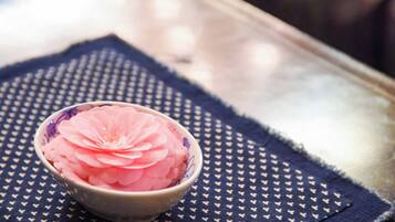 A bowl of pink flower petals on a patterned cloth.