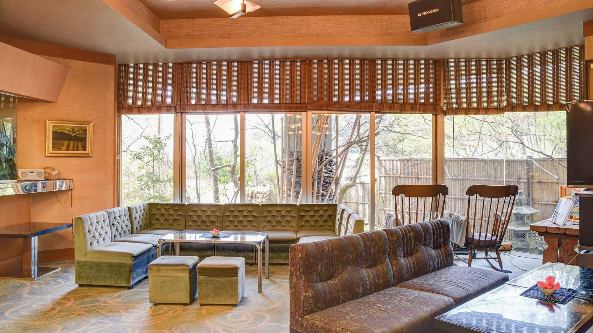 A modern living room with a large window, a sofa, a coffee table, and a dining area.