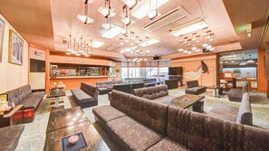 Un restaurante con varias zonas de estar, incluyendo cabinas y mesas, y una zona de bar con estantes llenos de botellas.