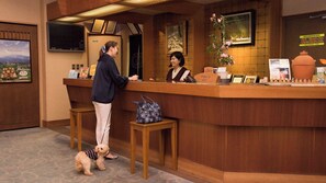 A reception desk with two staff members, a small table with a handbag, and a dog. - Aga No Megumi Bousenkaku (Gosen)