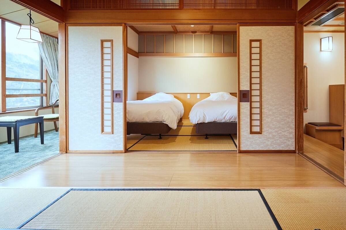 A traditional Japanese-style room with tatami flooring, two beds, a ladder, and sliding doors.