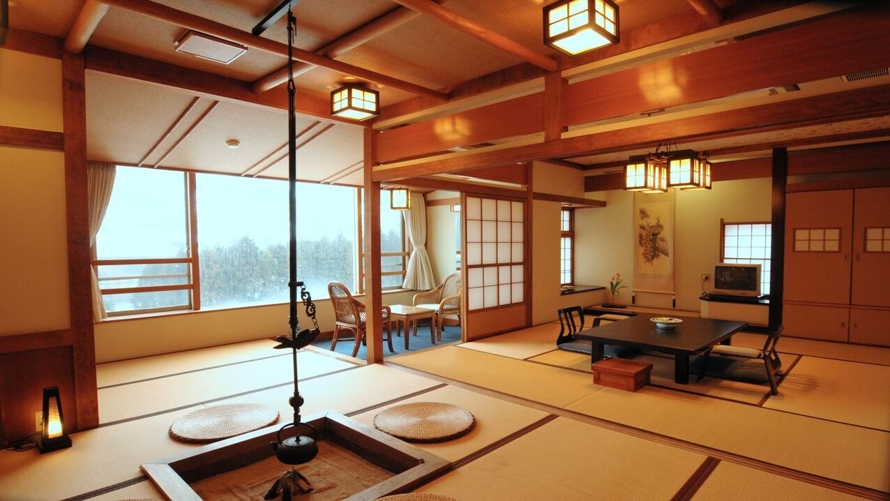 A traditional Japanese room with tatami flooring, low wooden tables, and sliding doors.