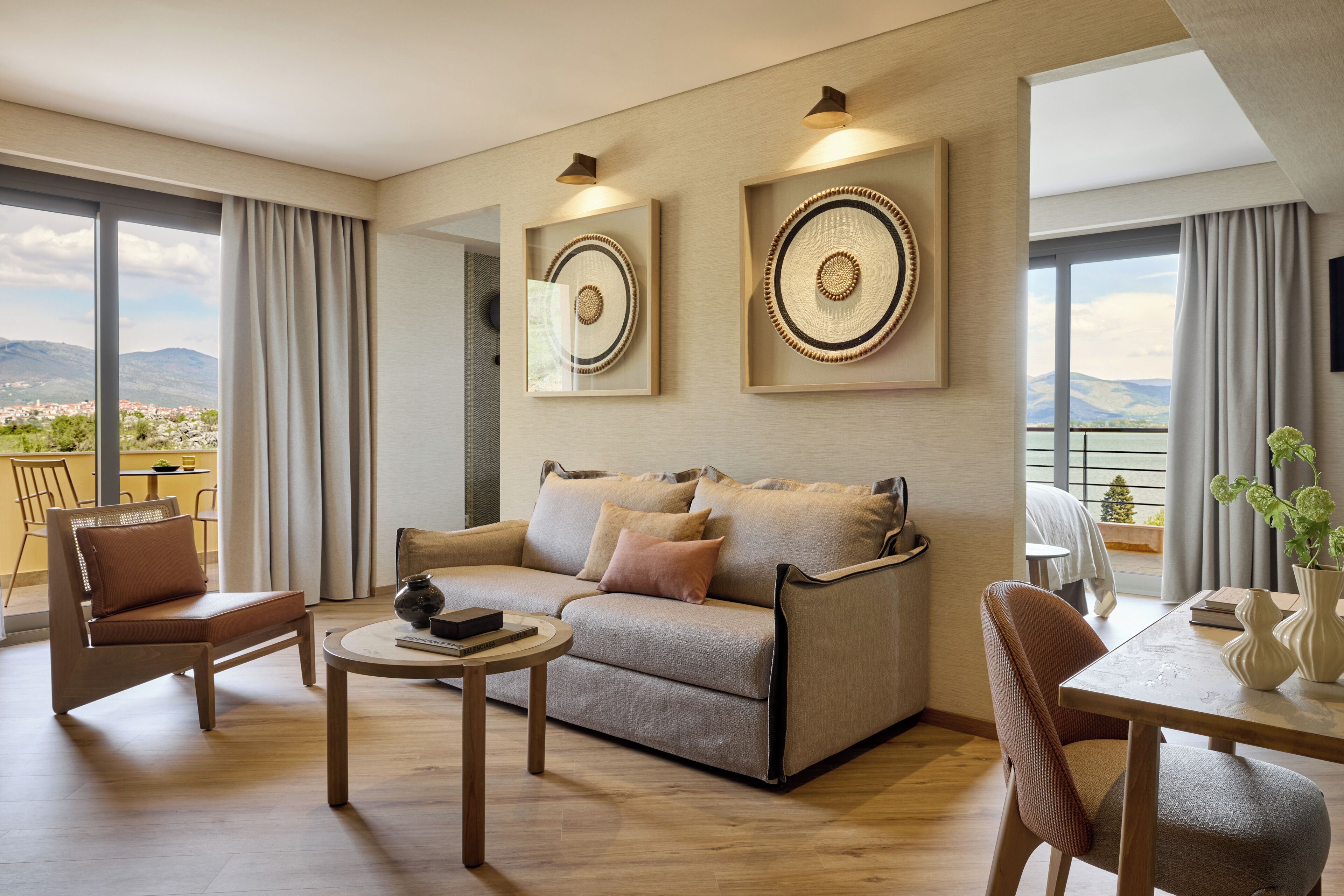 A modern living room with a sofa, chairs, a small table, and artwork on the walls.