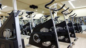 A gym with multiple stationary bikes arranged in rows.