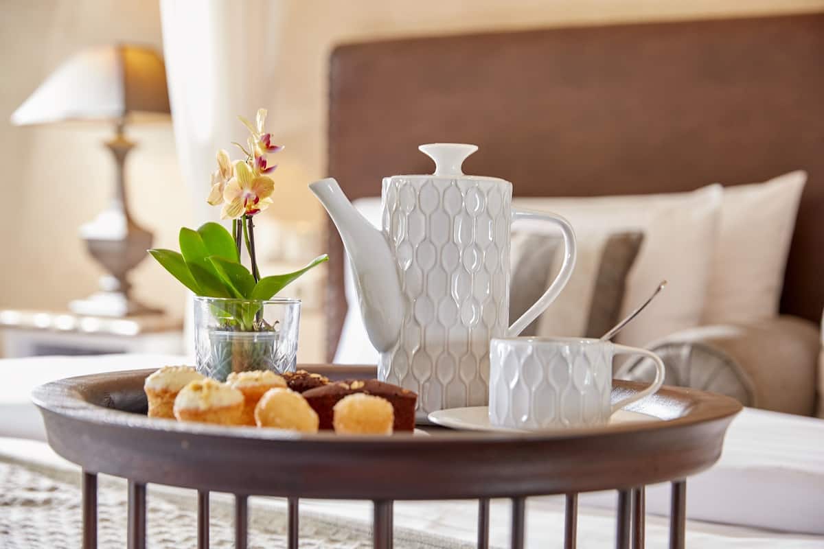 A tray with pastries, a teapot, and a cup on a table in a hotel room.