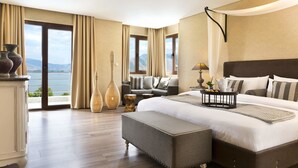 A spacious bedroom with a large bed, a sofa, and a view of the outdoors. - Limneon Resort & Spa (Kastoria)