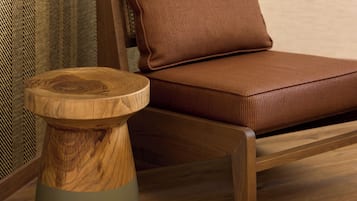 Une chaise en bois avec un coussin, un tabouret en bois et un mur orné de motifs.