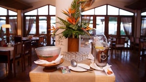 A dining table set with a glass bowl, a pitcher of orange juice, and a decorative plant arrangement. - Palissandre Hotel & Spa (Antananarivo)