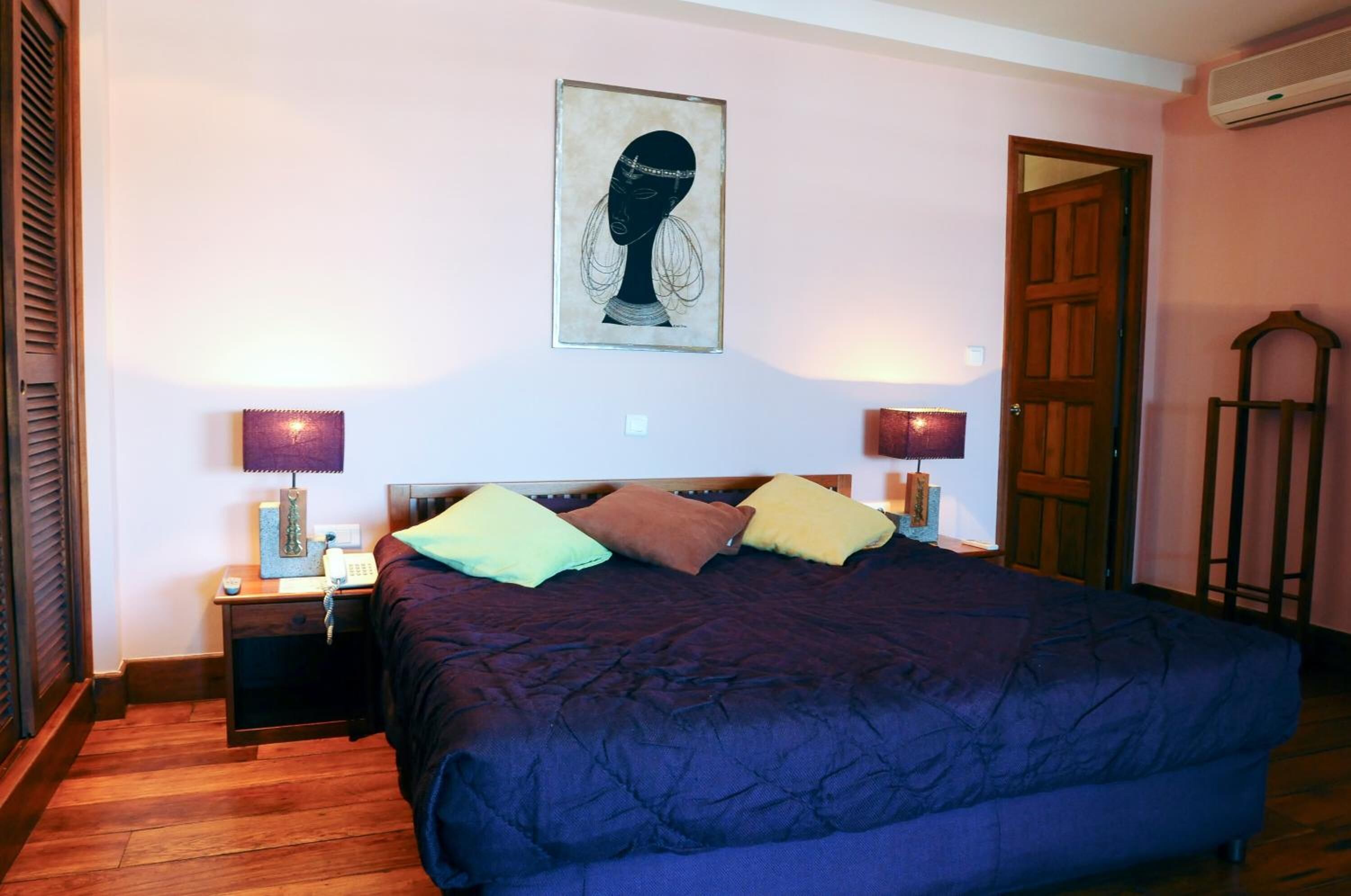 Une chambre à coucher avec un grand lit, deux tables de chevet avec des lampes, un plancher en bois et une porte.