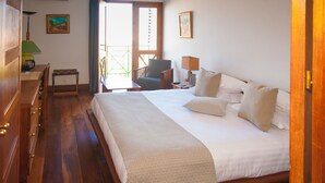 A hotel room with a large bed, wooden furniture, a desk with a lamp, and a chair. - Palissandre Hotel & Spa (Antananarivo)