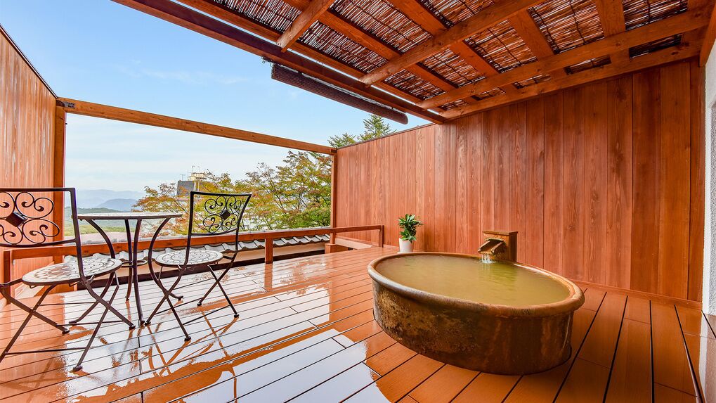 A wooden deck with a hot tub, outdoor seating, and a view of the mountains.