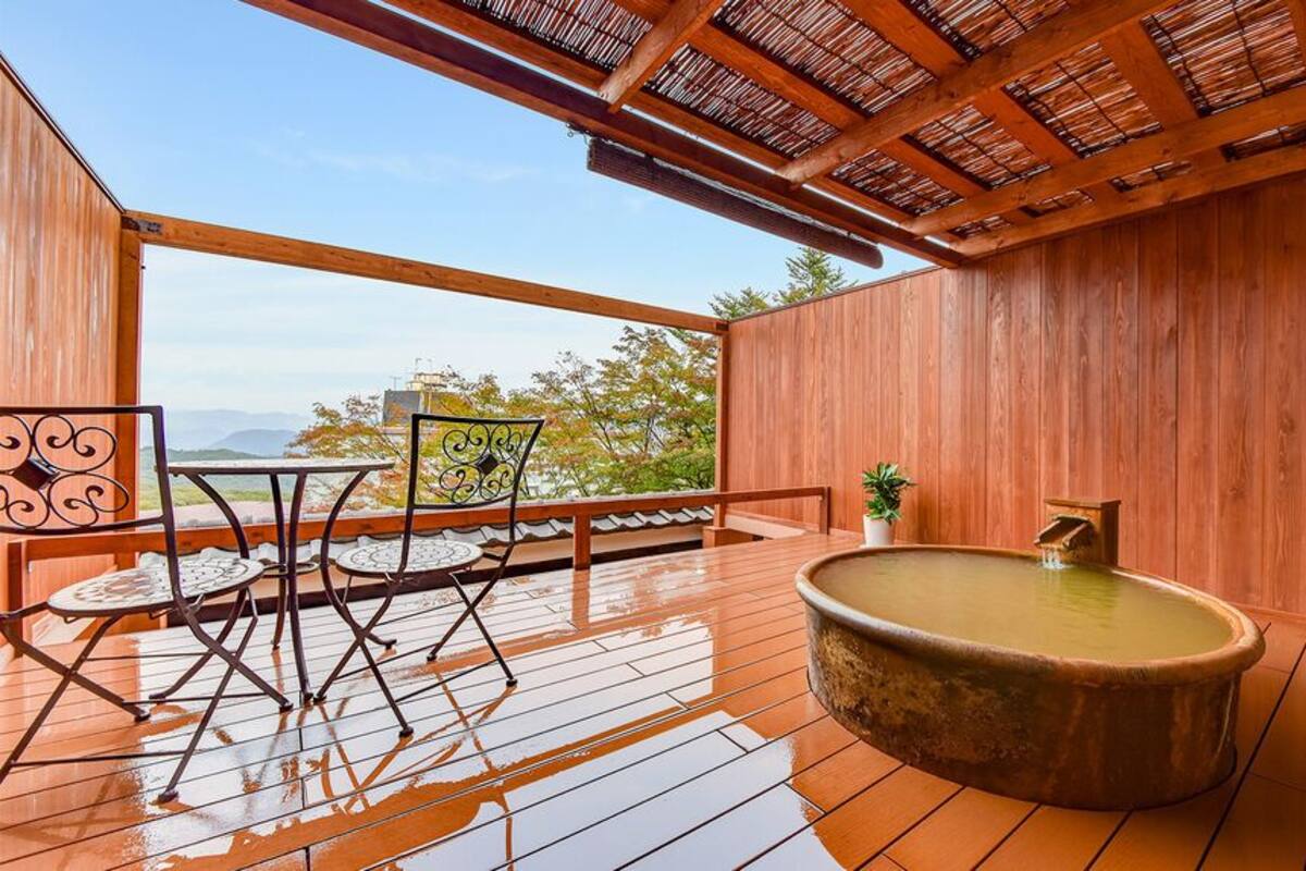 Une terrasse en bois avec un jacuzzi, un coin salon extérieur et une vue sur les montagnes.