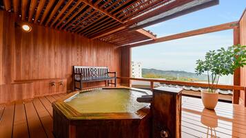 A wooden deck with a hot tub, a bench, and a potted plant.