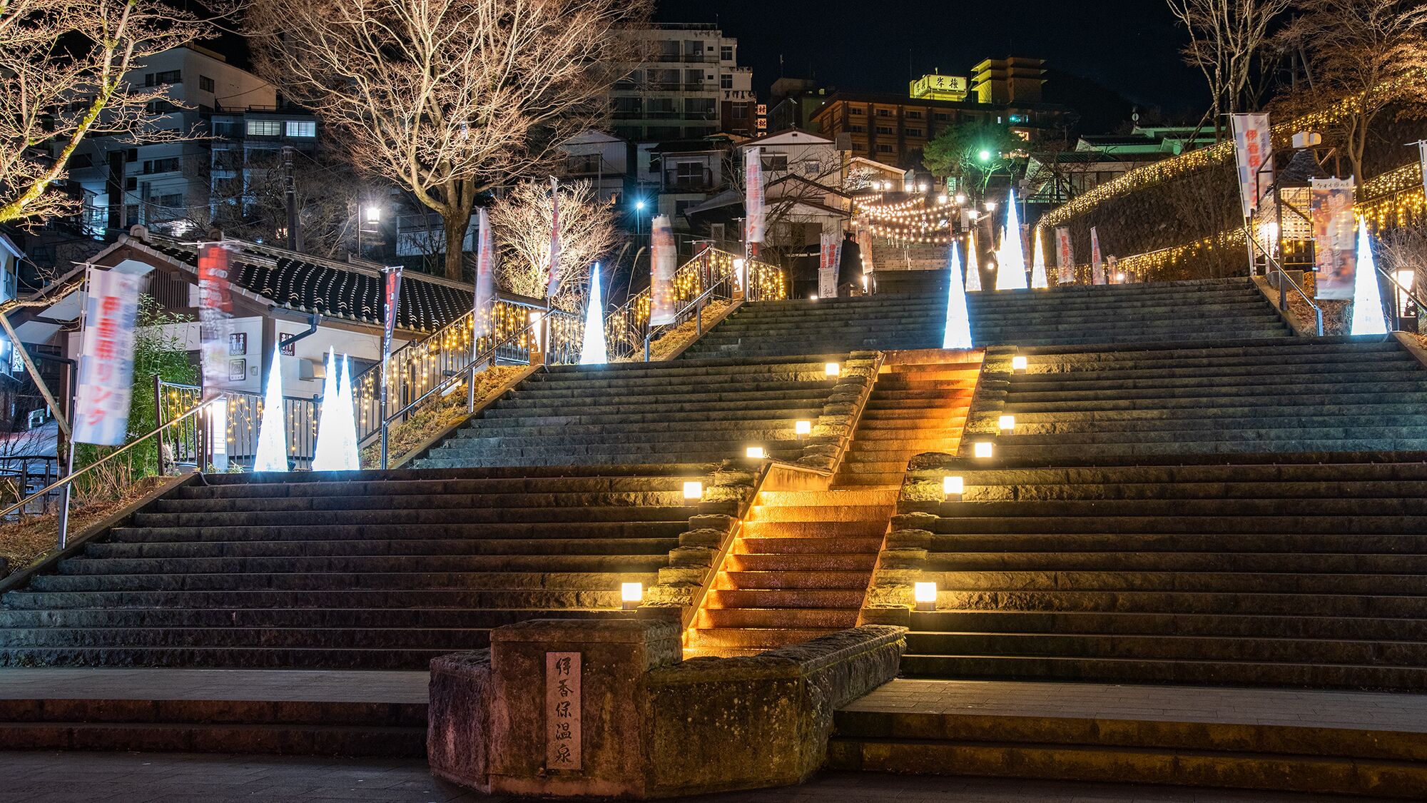 A nighttime view of a staircase with illuminated steps leading up to a building.