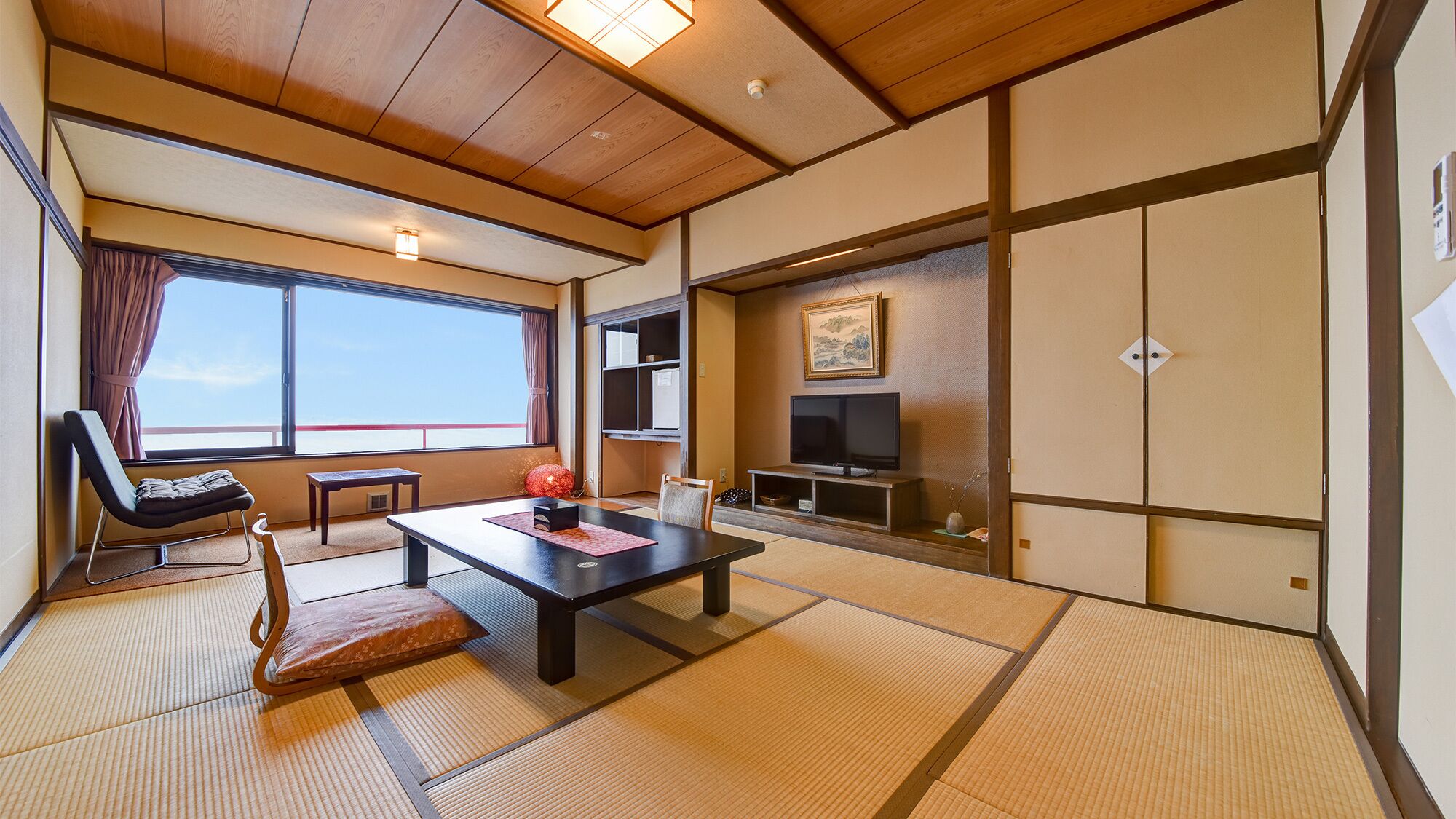 Quarto japonês tradicional com tatames, uma televisão, uma porta deslizante e vista para o céu.