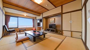Quarto japonês tradicional com tatames, uma televisão, uma porta deslizante e vista para o céu.