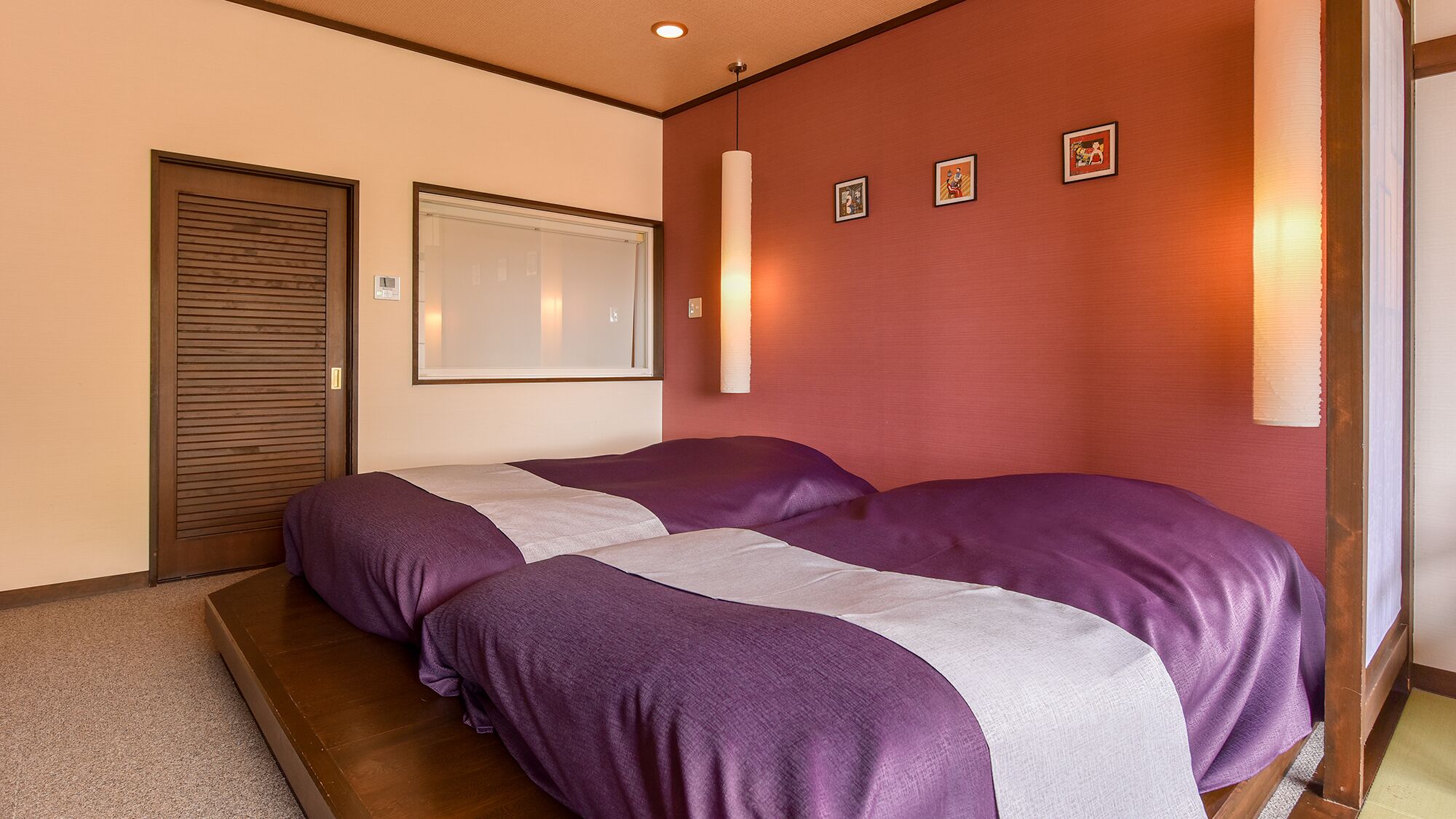 Habitación de hotel con cama, puerta, ventana y lámpara de pared.