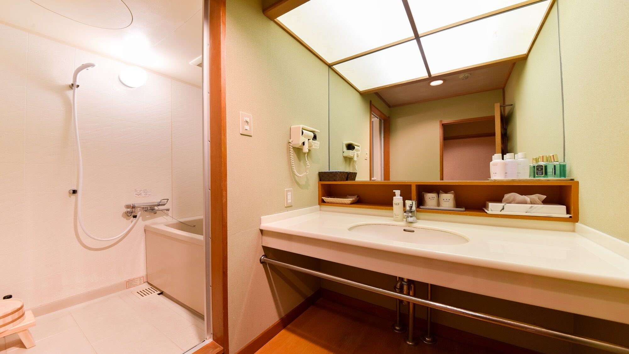 A bathroom with a shower, a sink with a mirror, and toiletries on the counter.