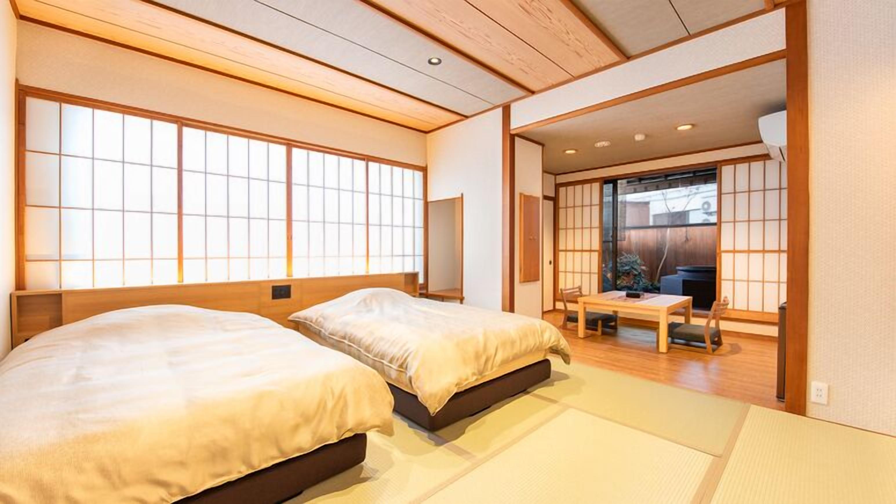 A traditional Japanese-style room with tatami flooring, two beds, a sliding door leading to a balcony, and a low wooden ceiling.