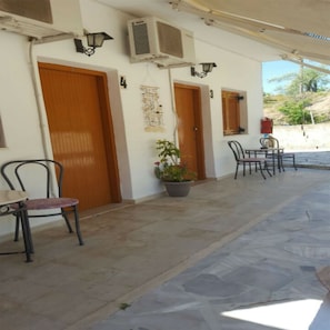 An outdoor seating area with stone flooring, two doors, and a potted plant. - Pension Nychterida (Corfu)