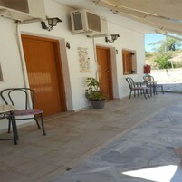 Un área de estar exterior con suelo de piedra, dos puertas y una planta en maceta.