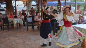 A traditional dance performance in an outdoor setting with stone flooring and tables set for an audience. - Pension Nychterida (Corfu)