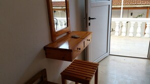 A wooden bench, a small table, and a door with a white doorbell. - Pension Nychterida (Corfu)