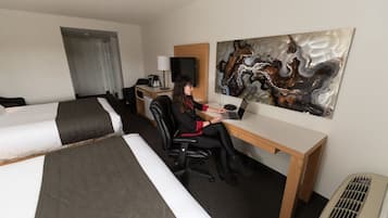 A hotel room with two beds, a desk, a chair, a television, and a painting on the wall.
