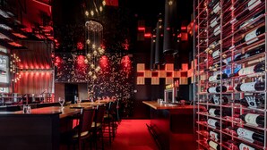 Eine moderne Bar mit Weinkühler, Barhocker und einer Pendelleuchte.