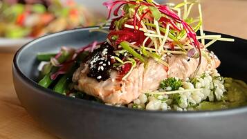 Un plato de comida con salmón, vegetales verdes y una decoración.