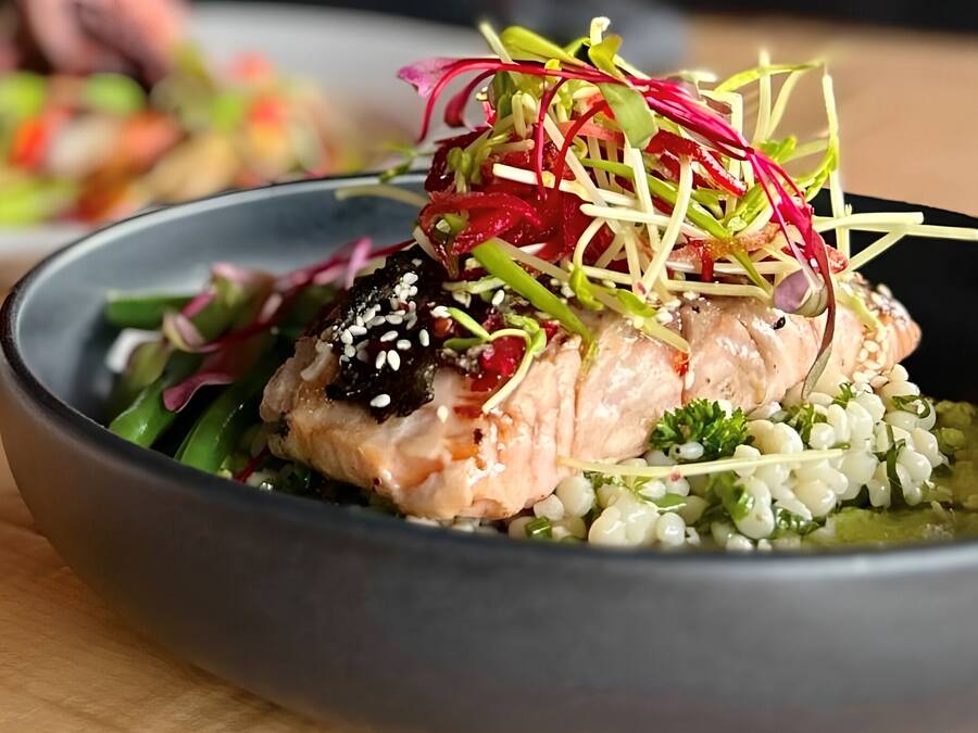 Un plato de comida con salmón, vegetales verdes y una decoración.