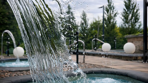 Ein Wasserspiel mit einem großen Wasserstrahl und kugelförmigen Elementen in einer angelegten Grünfläche.