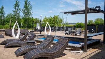 A pool area with lounge chairs, a small pool, and a pergola.