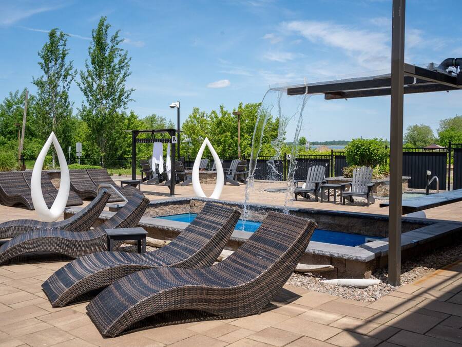 Un área de piscina con sillones de descanso, una piscina pequeña y una pérgola.