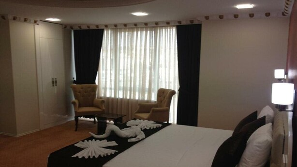 A hotel room with a bed, two armchairs, a small table, and a wardrobe. - Elite Marmara Residence (Istanbul)