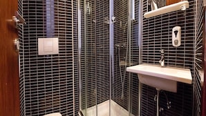 A modern bathroom with a glass-enclosed shower, a white sink, and a toilet. - Sirena Hotel (Podgora)