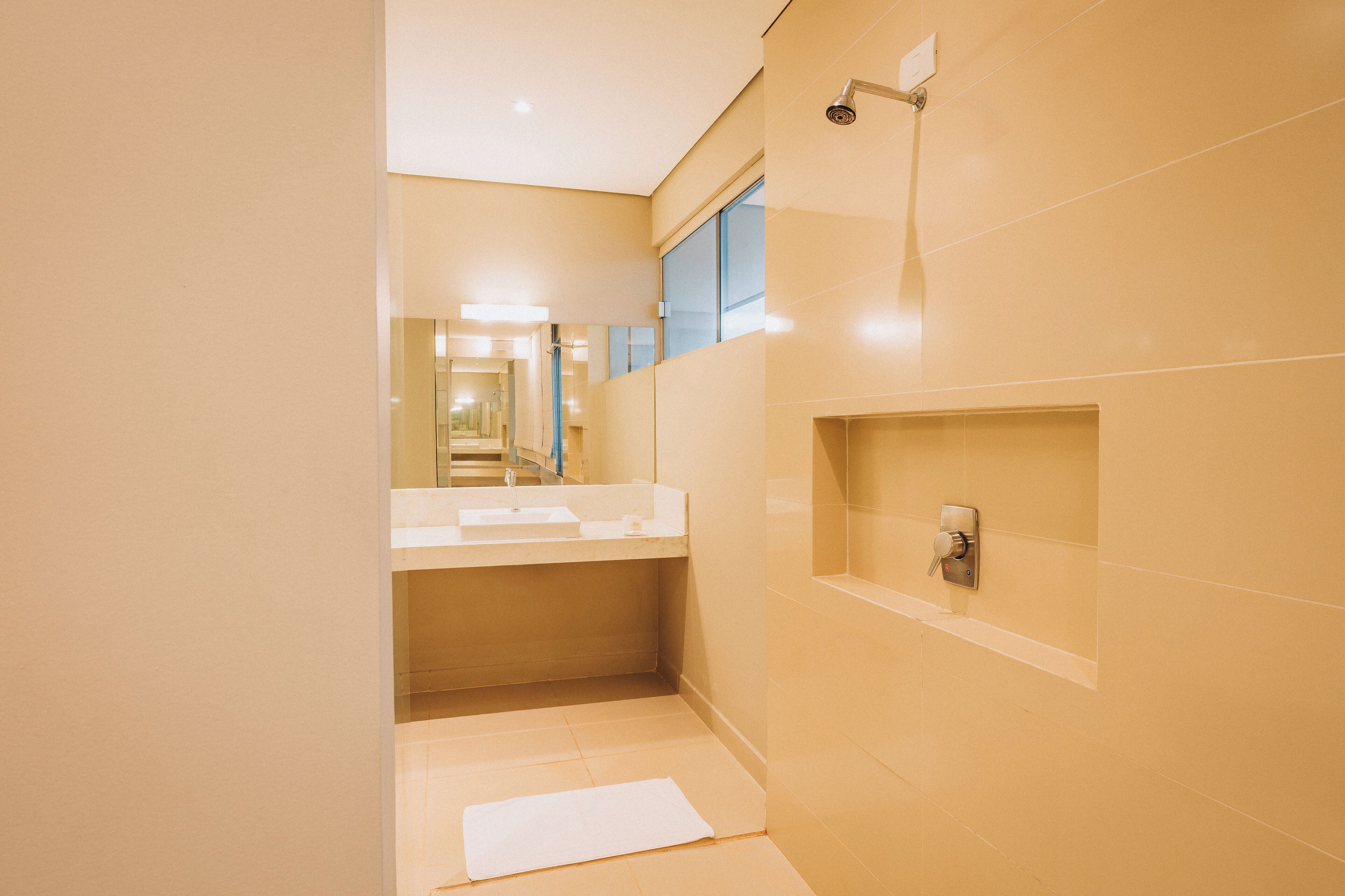 A modern bathroom with a large mirror, a sink, and a shower.